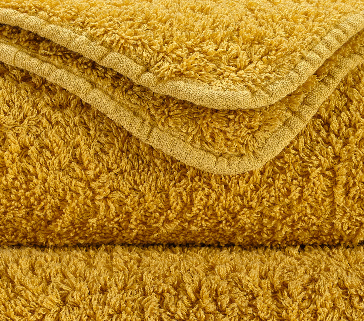 Premium towel set in the finest Giza 70 cotton in Gold – luxurious bathroom textile by Tiamont, matching refined bathroom furniture and stylish interiors. Handmade in Portugal.